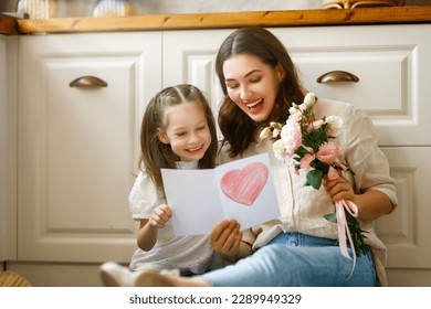 Happy mother's day. Child daughter congratulating her mother and giving her bouquet of flowers. Stock Photo