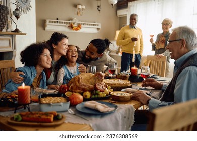 Happy multiracial parents and their kids laughing during family meal on Thanksgiving in dining room. , fotografie de stoc