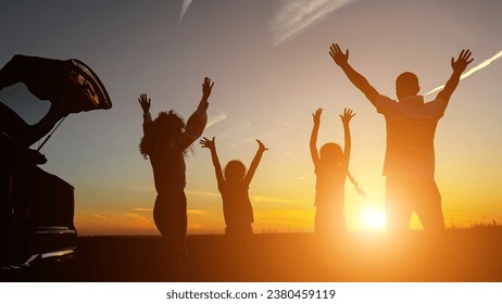 Des parents heureux avec des enfants se lèvent la main près d'un véhicule donnant sur le coucher du soleil le soir. Concept de passer du temps en famille et observer les beautés de la nature, la lumière du soleil : photo de stock