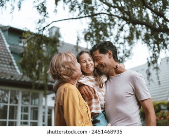 Happy parents embracing daughter standing in front of house - Φωτογραφία στοκ