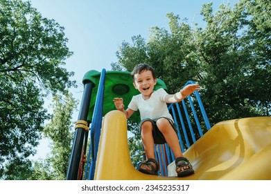 여름에 놀이터에서 미끄럼틀을 타는 행복한 미취학 소년 스톡 사진
