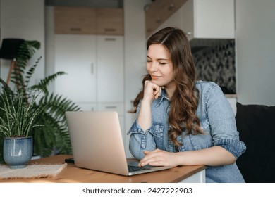 Happy smiling woman sitting on couch, couch and using laptop in living room at home, watching funny video, learning language, video calling, mother working online. Woman Working Online On Laptop At Adlı Stok Fotoğraf