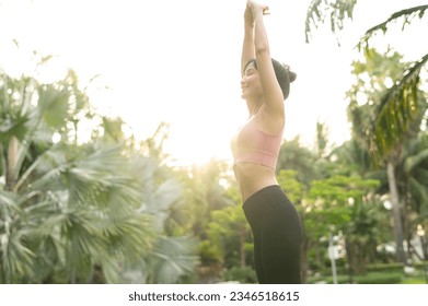 healthy outdoor lifestyle fit young Asian woman 30s in pink sportswear engages in yoga and stretches muscles in public park at sunrise. concept of wellness and well being with fitness yoga girl. Foto stock