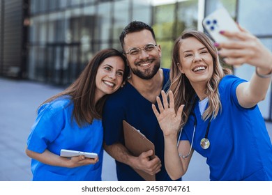 Healthcare workers selfie at work. Multiracial doctors and nurses taking picture using smartphone. Close up of Diverse medicine students in uniform taking selfie in front of Hospital Stockfoto