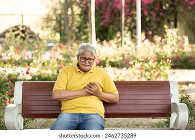 Heart attack concept.. Indian Senior man suffering from chest pain outdoor in park, Foto stock