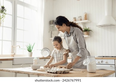 ヒスパニックの女性は小さな娘に料理を教え、ペストリーのための自家製の生地を準備し、自宅のキッチンで週末の余暇に休日のパイやクッキーを作ります。天然物、健康的な食事、子供の発達の写真素材