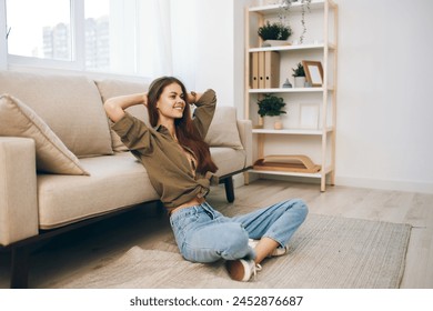 Home Comfort: Happy Woman Relaxing on a Cosy Sofa in Modern Apartment ภาพถ่ายสต็อก