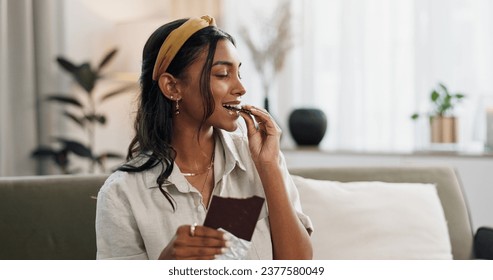 Home, relax and woman with chocolate bar, smile and eating with candy, hungry and dessert. Person, apartment or girl on a sofa, candy or sweet treats with a snack, nutrition or diet plan with cacao Arkistovalokuva