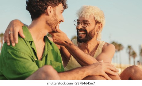 Homosexual couple in love sits on the beach hugging and looking at each other with love Foto stock