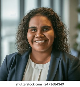 Indoor photo of portrait of a young smiling aboriginal australian woman in business attire in office