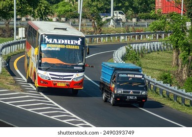 有料道路上で無謀またはスピードを上げていたダリ・マスという都市間バスがピックアップ車を追い越した、インドネシア、2024年7月16日。のエディトリアル写真素材