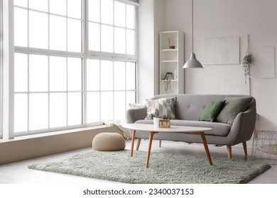 Interior of light living room with grey sofa, coffee table and big window Arkistovalokuva