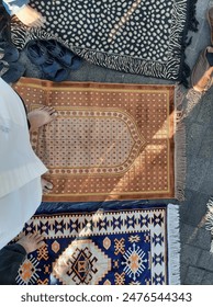 An intricately patterned prayer mat used during Eid al-Adha morning prayer, symbolizing devotion and reflection. Soft sunlight illuminates the scene, enhancing the serene atmosphere of this religious 庫存照片