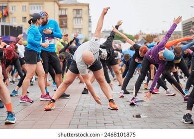 Ivano-Frankivsk, Ukraine - October 8, 2023: excited competitors warming up before running. Big crowd preparing for half marathon. Exercising outdoor. Foto Editorial Stock