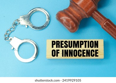 裁判官の小槌、鉄の手錠と無実の推定という言葉を持つ木材。罪悪感と裁判所の概念の写真素材