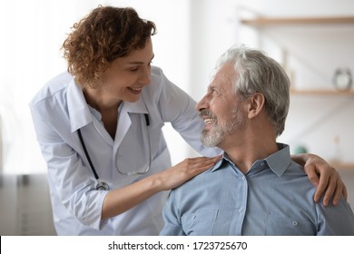 優しい笑顔の女性医師が、元気の良い高齢男性患者を入院させる。老人ホームで話すのを楽しんでいる幸せな健康な老人と医師。高齢者医療のコンセプト。の写真素材