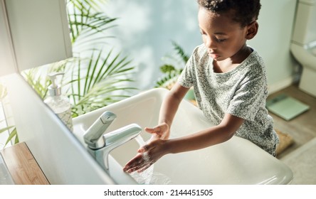 Kids should wash their hands often with soap and water. High angle shot of a boy washing his hands at a tap in a bathroom at home. Stock Photo
