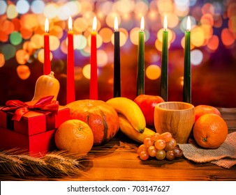 Kwanzaa vakantie concept met versieren zeven kaarsen rood, zwart en groen, geschenkdoos, pompoen, kom en fruit op licht vervagen bokeh achtergrond: stockfoto
