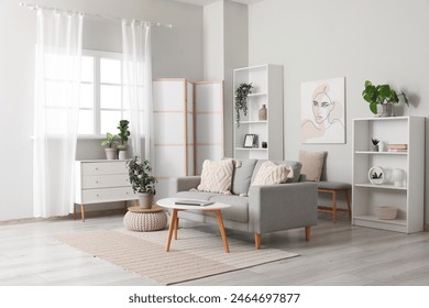 折り畳み式スクリーン、快適なソファ、コーヒーテーブル、引き出しの胸を持つ軽いリビングルームの写真素材