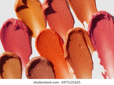ベージュ背景に口紅ピンクと赤のオレンジの茶色のパレット汚れの背景テクスチャーの写真素材