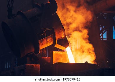 Liquid iron molten metal pouring from ladle container into mold, industrial metallurgical factory, foundry cast, heavy industry background Foto stock