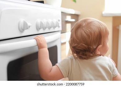 屋内でガスストーブで遊んでいる小さな子供。台所での危険の写真素材