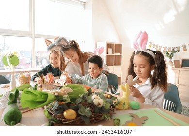 テーブルでイースターの工芸品を作るウサギの耳に小さな子供たちの写真素材