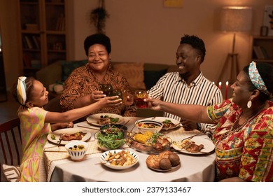 Little girl clinking glasses with family dinner at Kwanzaa holiday dinner: stockfoto
