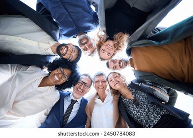 Low angle view of cheerful group of diverse business people in formal wear are gathered in a circle, sharing smiles embracing together as a gesture of unity and celebration success at a formal event 庫存照片