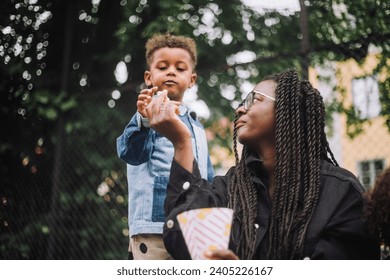 Low angle view of mother giving popcorn to son at amusement park Stock Photo