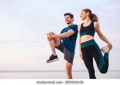 Lower couple young two friend strong sporty sportswoman sportsman woman man in sport clothes warm up training do stretch exercise on sand sea ocean beach outdoor jog on seaside in summer day morning Stock-foto