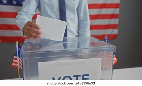 A man casting a vote in an american election with a ballot box and us flags, representing democracy and citizenship. Arkistovalokuva