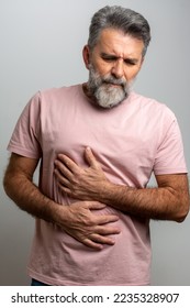 A man touching his stomach, on gray background with copy space. Stomach pain and others stomach disease concept. Vertical. hand on stomach because indigestion, painful illness feeling unwell. ache  Arkistovalokuva