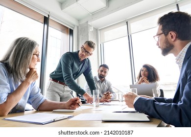 Male mature caucasian ceo businessman leader with diverse coworkers team, executive managers group at meeting. Multicultural professional businesspeople working together on research plan in boardroom. Stock-foto