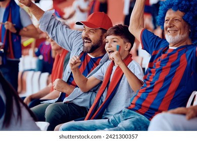 スタジアムのスタンドから試合を見ている間、彼らのスポーツチームのために応援する家族の男性。  の写真素材