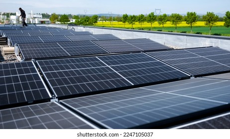 独立型太陽光発電パネルシステムを設置する男性のチームエンジニア。会社の屋根の屋根に青い太陽電池モジュールを取り付ける電気技師。代替エネルギー概念の写真素材
