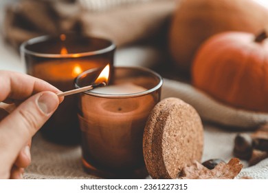Match in hand lights a candle, cosiness concept. Foto Stock