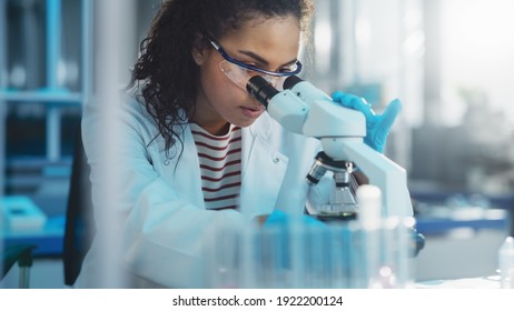 의학 연구소: 현미경으로 관찰하고 있는 아름다운 흑인 과학자의 초상화는 실험 표본을 분석한다. Advanced Equipment 와 함께 일하는 야심찬 젊은 생물 공학 전문가 스톡 사진