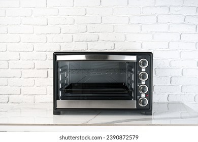 Mini electric oven against white brick wall in the kitchen Arkistovalokuva