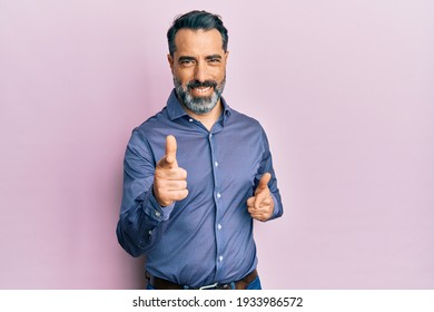 Стоковая фотография: Middle age man with beard and grey hair wearing business clothes pointing fingers to camera with happy and funny face. good energy and vibes. 