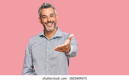 Стоковая фотография: Middle age grey-haired man wearing casual clothes smiling friendly offering handshake as greeting and welcoming. successful business. 