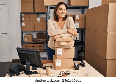 Middle age hispanic woman working at small business ecommerce winking looking at the camera with sexy expression, cheerful and happy face.  ภาพถ่ายสต็อก