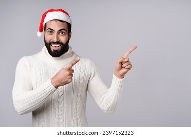 산타의 빨간 모자를 쓴 중동의 아라비아 남자는 회색 배경에 고립된 카피스페이스 빈 공간을 보여준다. 크리스마스 새해 축하. 스톡 사진
