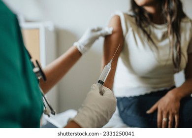 Midsection of female doctor giving vaccine to young woman in clinic Arkistovalokuva