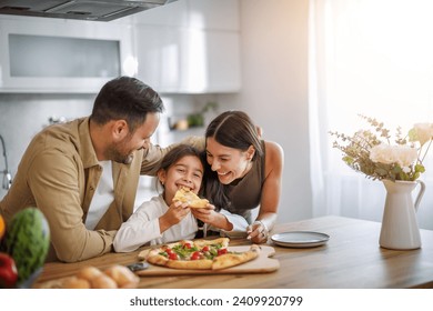 Mom, dad and daughter are eating together at home. Happy family eating pizza at home. Stock-foto
