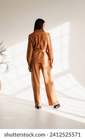model in suit posing in studio.Fashion model  dressed in a beige,brown  
office suit posing in the studio on a white ciclorama Arkistovalokuva