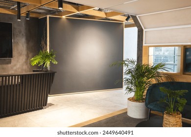 In modern office lounge, green plants adding life to space. Comfortable seating and warm lighting create a welcoming atmosphere, unaltered Foto Stock