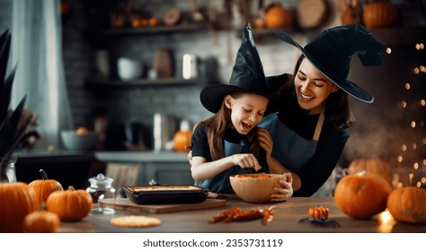 Mother and her daughter having fun at home. Happy Family preparing for Halloween. Mum and child cooking festive fare in the kitchen. Stock Photo
