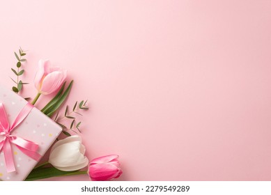 Mother's Day concept. Top view photo of stylish pink giftbox with ribbon bow and bouquet of tulips on isolated pastel pink background with copyspace Stock Photo