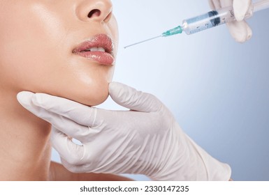 青の背景にスタジオで美容外科用の女性の顔に手で口、ボトックスと形成手術。唇、フィラーまたは美しさと注射のための彼女の医者と女性患者の写真素材